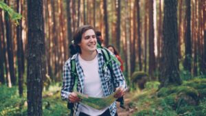 Young hikers with backpacks consult a map in a forest.
